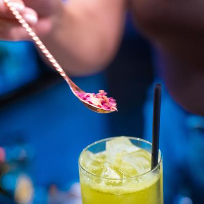 Cocktail being garnished with dried flower petals.