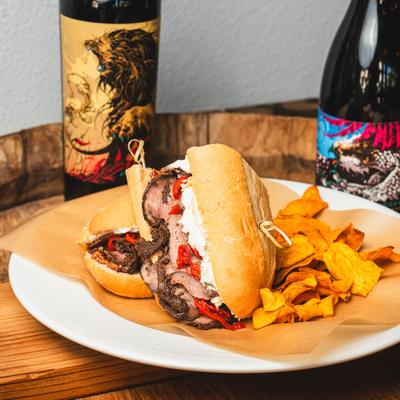 The Lemmy sandwich with chips, accompanied with assorted  wine bottles.