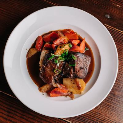 Braised short ribs with mashed potatoes, roasted vegetables, and demi-glace.