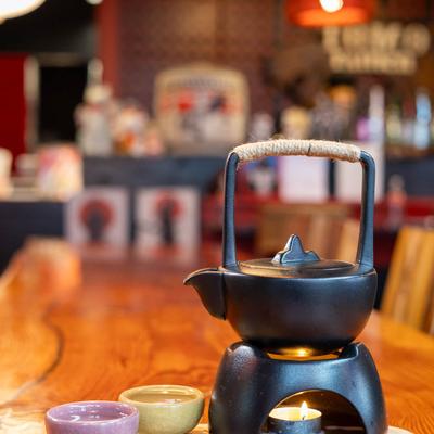 A black teapot heated with a candle surrounded by colorful teacups.