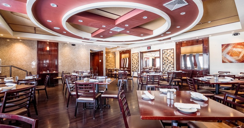 A restaurant dining area with wooden tables and chairs, a circular ceiling design