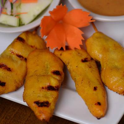 Banana fritters, served with a salad and a sauce, leaf-shaped carrot garnish.