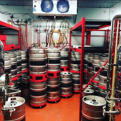 Stacked silver kegs in a storage room.