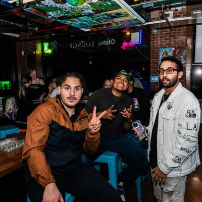 Three guests posing together inside the  lively gaming lounge.