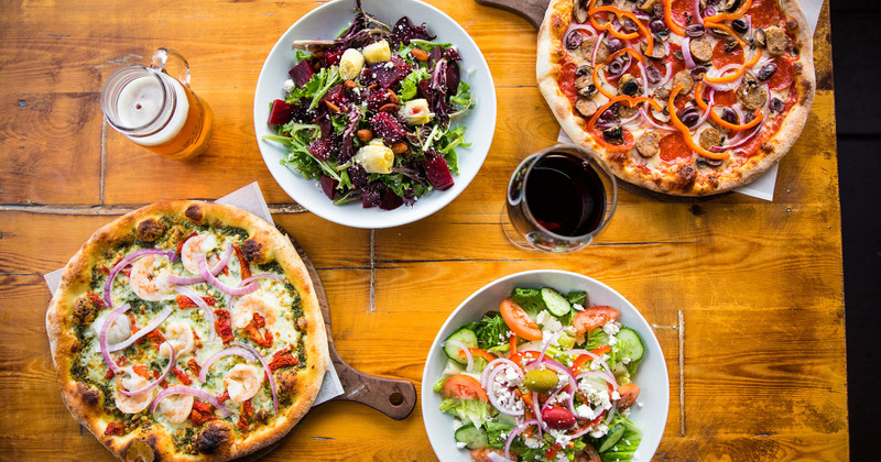 Two different pizzas, two salads, a glass of wine and a glass of beer