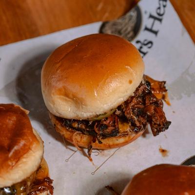 Pulled pork slider with sauce served on deli paper.