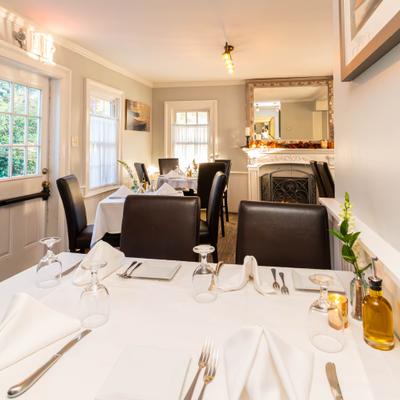 Interior with tables set for dining and a fireplace in the background.