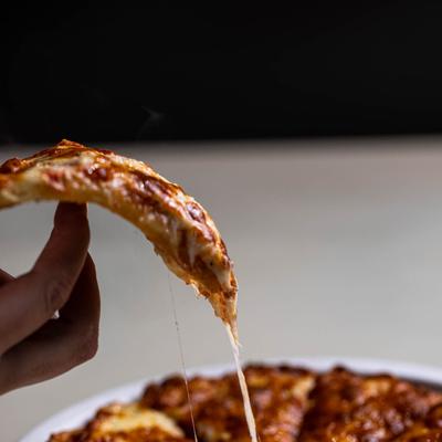 Slice of pizza held, cheese pull shot