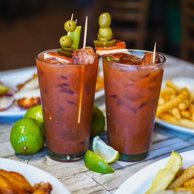Two Bloody Mary cocktails with garnishes.