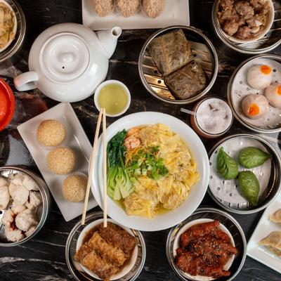 Various dim sum dishes on a table, including dumplings, noodles, and steamed buns.