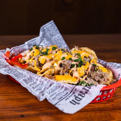 Basket of Pulled Pork Nachos topped with melted cheese and scallions.