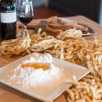 Classic culinary setup for making fresh homemade pasta displayed alongside red wine.