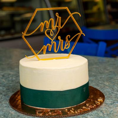 Navy blue and white wedding cake with decoration on top.