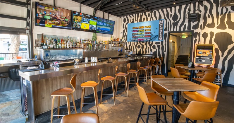 Interior, Trendy bar with zebra-striped walls, a long counter, and tan leather barstools