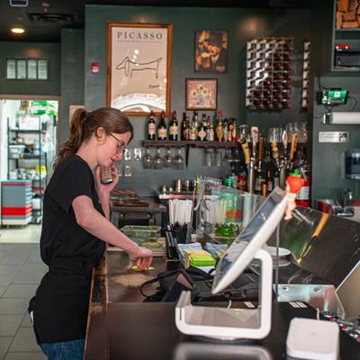 Person working behind bar counter inside a restaurant.