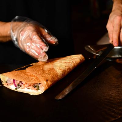 Hands in gloves preparing a stuffed crepe.