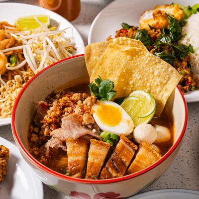 Tom Yum Noodle Soup with minced pork, pork belly, a soft-boiled egg and fried wontons.