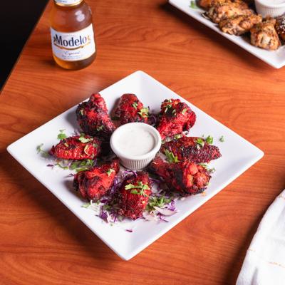 Tandoori wings with dipping sauce served with a bottle of beer.