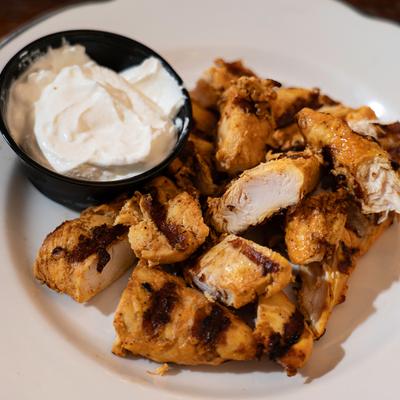 Sliced grilled chicken with a creamy sauce dip.