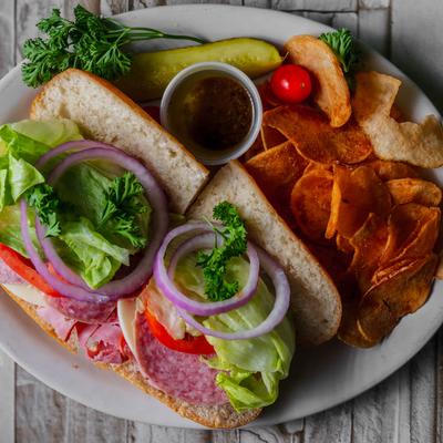 Italian sub sandwich with ham and salami, served with chips and dipping sauce.
