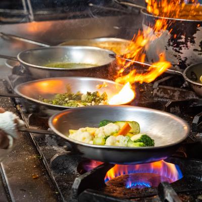 A chef preparing food on a stovetop with several pans.