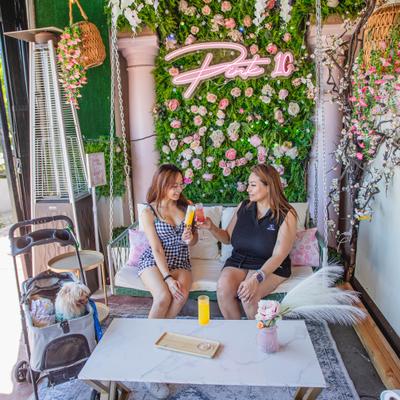 Two people are sitting on a white garden swing surrounded by floral decor and greenery.