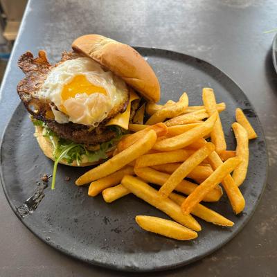 Bangkok Burger and fries on a round dark plate.
