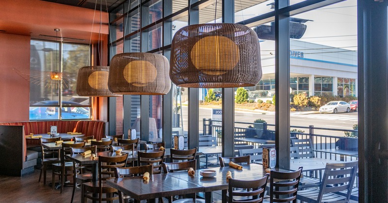 Dining tables and a half circle booth by a window side, hanging scone lanterns