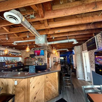 Interior with a wooden bar top, exposed wooden ceiling beams and industrial ductwork.