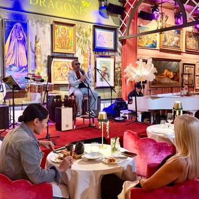 Two ladies at the table eating while the bolero singer is on the stage.