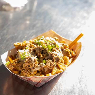 A serving of fries loaded with pulled pork, melted cheese and scallion.