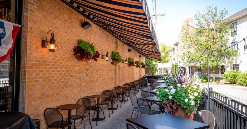 Exterior, outdoor seating, brick wall, striped canopy, hanging plant pots