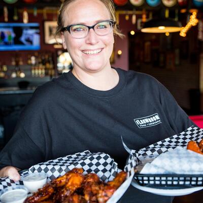 Smiling Staff member serving baskets of chicken wings