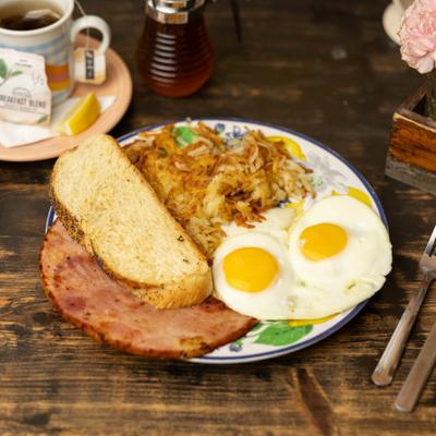 Sunny side up eggs with ham,  hash browns, and toast.