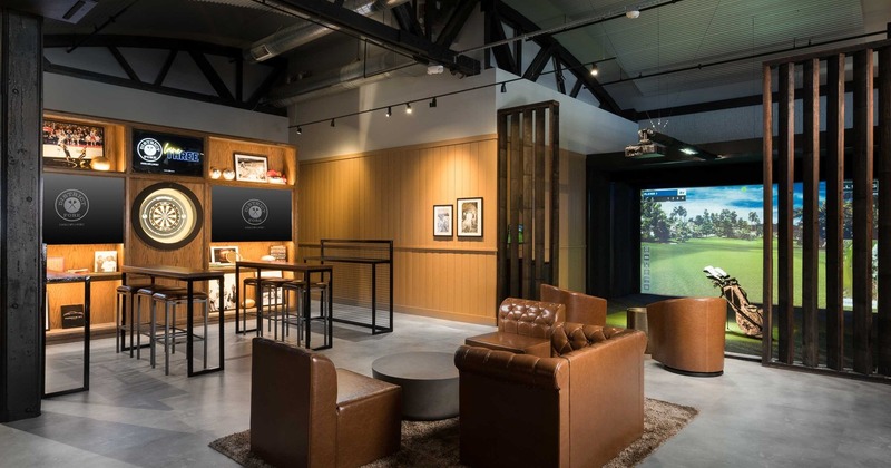 Interior, golf simulator room with a small lounge and bar seating in front