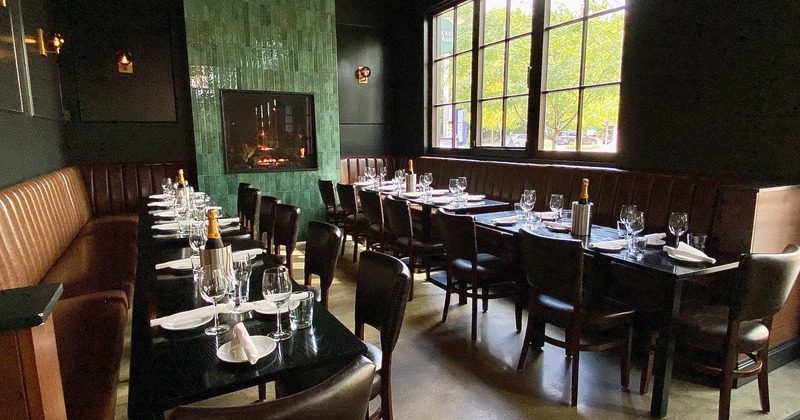 Banquette seating with tables set with tableware and a wall fireplace