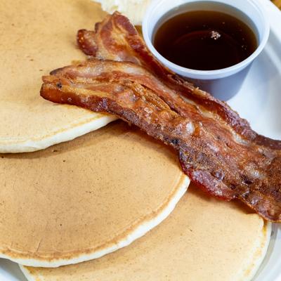 Pancakes served with bacon and syrup.