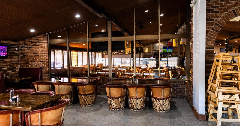 Spacious restaurant interior with brick walls, wooden tables, and leather chairs