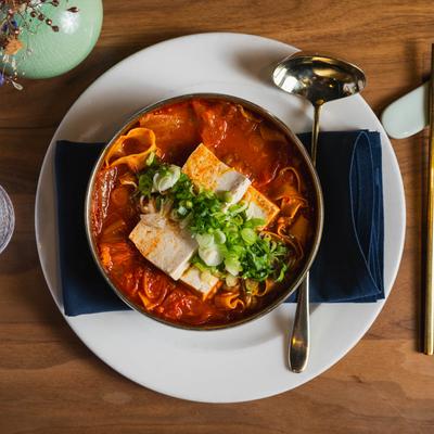 Kimchi Stew, with garlic, pork belly, tofu, noodles, and scallions.