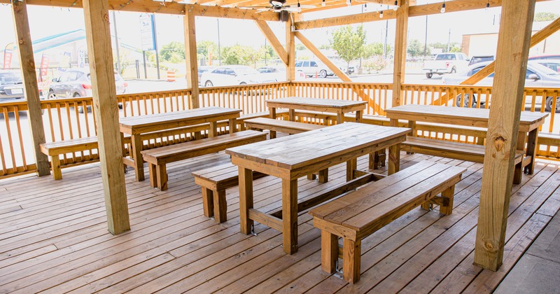 Exterior, covered patio with wooden tables and benches