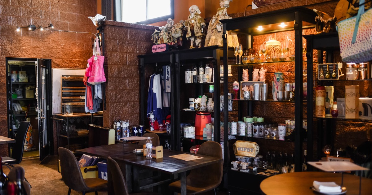 Interior, seating area, table for four, shelves with winery merch, red block walls