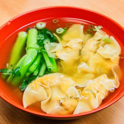 Wonton soup with bok choy in red bowl.