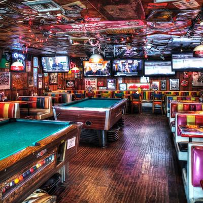 Interior, wooden floors and colorful retro booths, two pool tables sit in the center