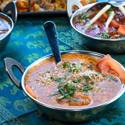 Paneer Tikka Masala and other curry dishes served on a green patterned tablecloth.