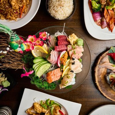 A vibrant platter of assorted sashimi with garnishes like lemon, cucumber, and flowers.