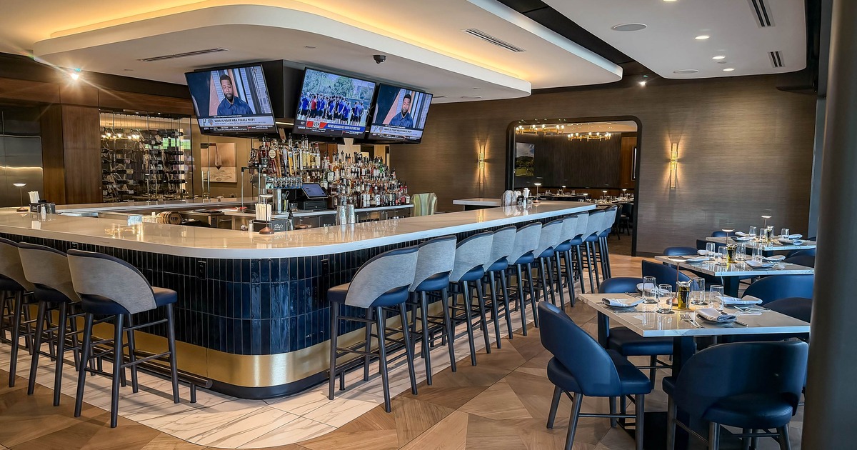 A modern restaurant bar with a curved white countertop, high stools
