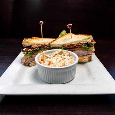 Turkey club sandwich accompanied by coleslaw.