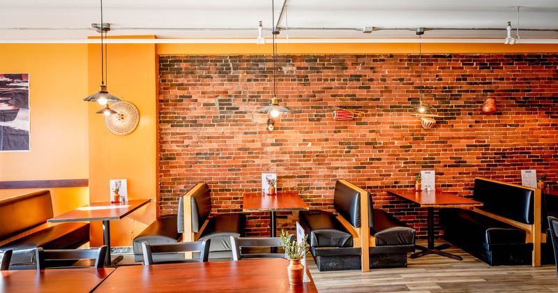Rustic interior with brick walls, wooden booths, pendant lights and wooden tables