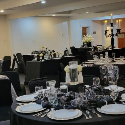 Elegant event space featuring circular tables with black linens and white plates.