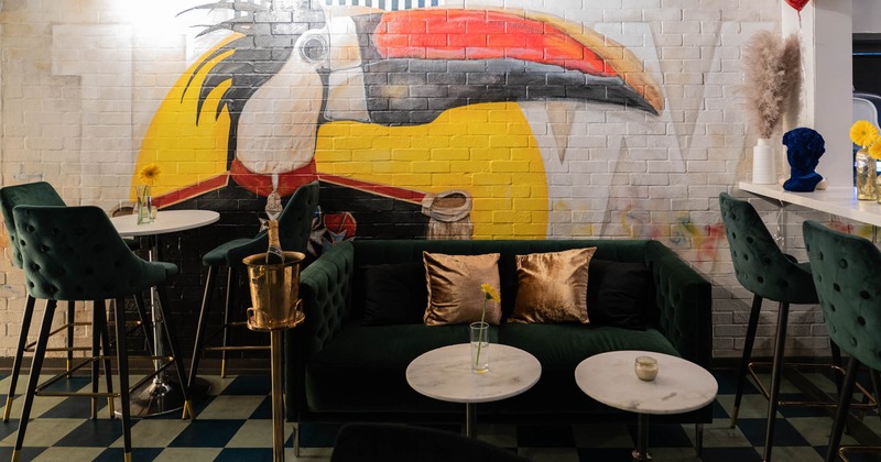 Booth with tables and stools, painting on the wall